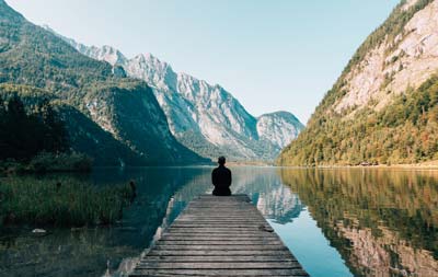 Photo d'un homme en méditation sur un ponton.